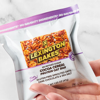 Lexington Bakes cocoa cereal protein oat bar in packaging, held in hand